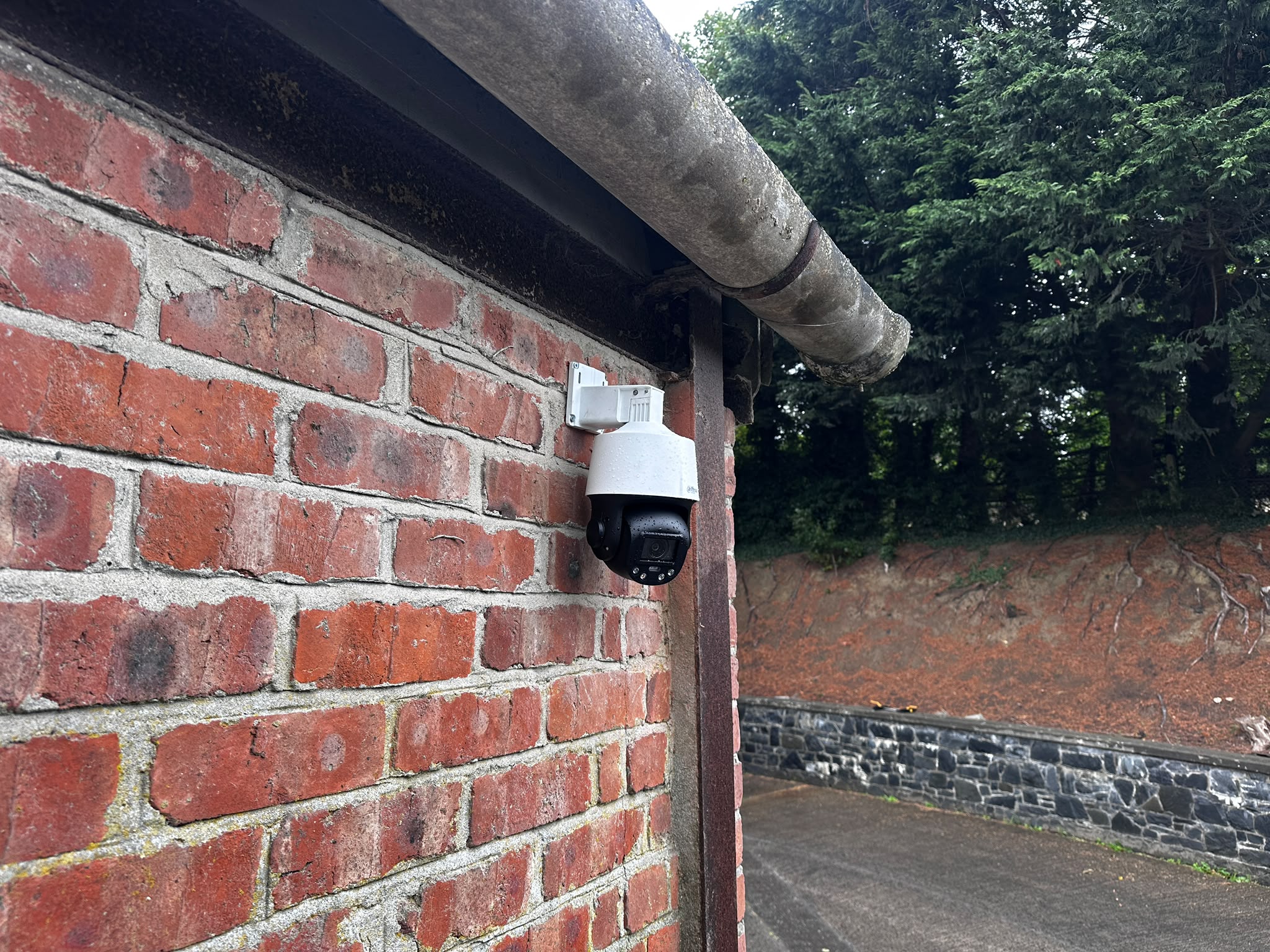 Pan-tilt-zoom security camera fitted under the eaves at the side of the salon